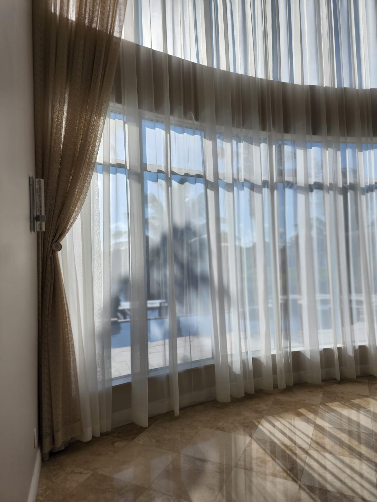 Soft sheer drapery installed over tall glass doors in Miami